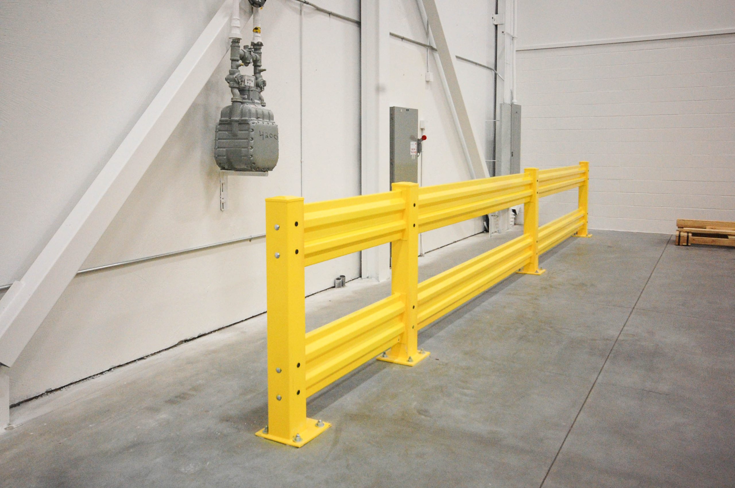 Barrière de protection industrielle jaune installée pour sécuriser une zone de circulation dans un entrepôt